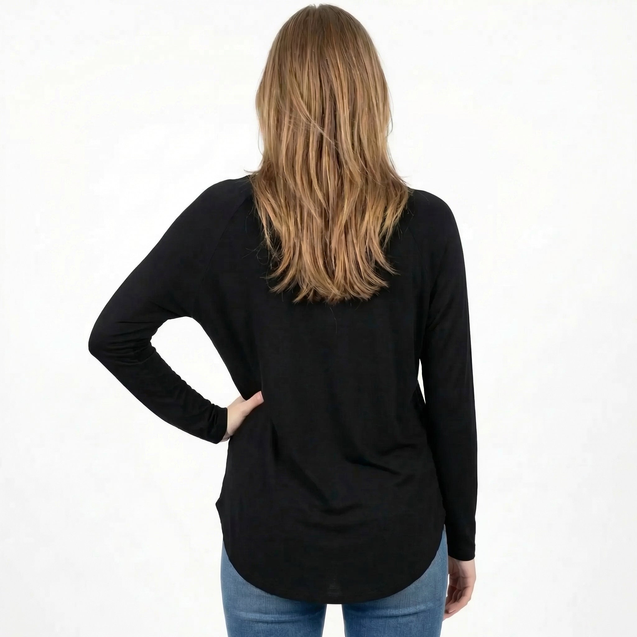 Woman wearing black long sleeve travel top, back view, paired with jeans for comfortable everyday wear