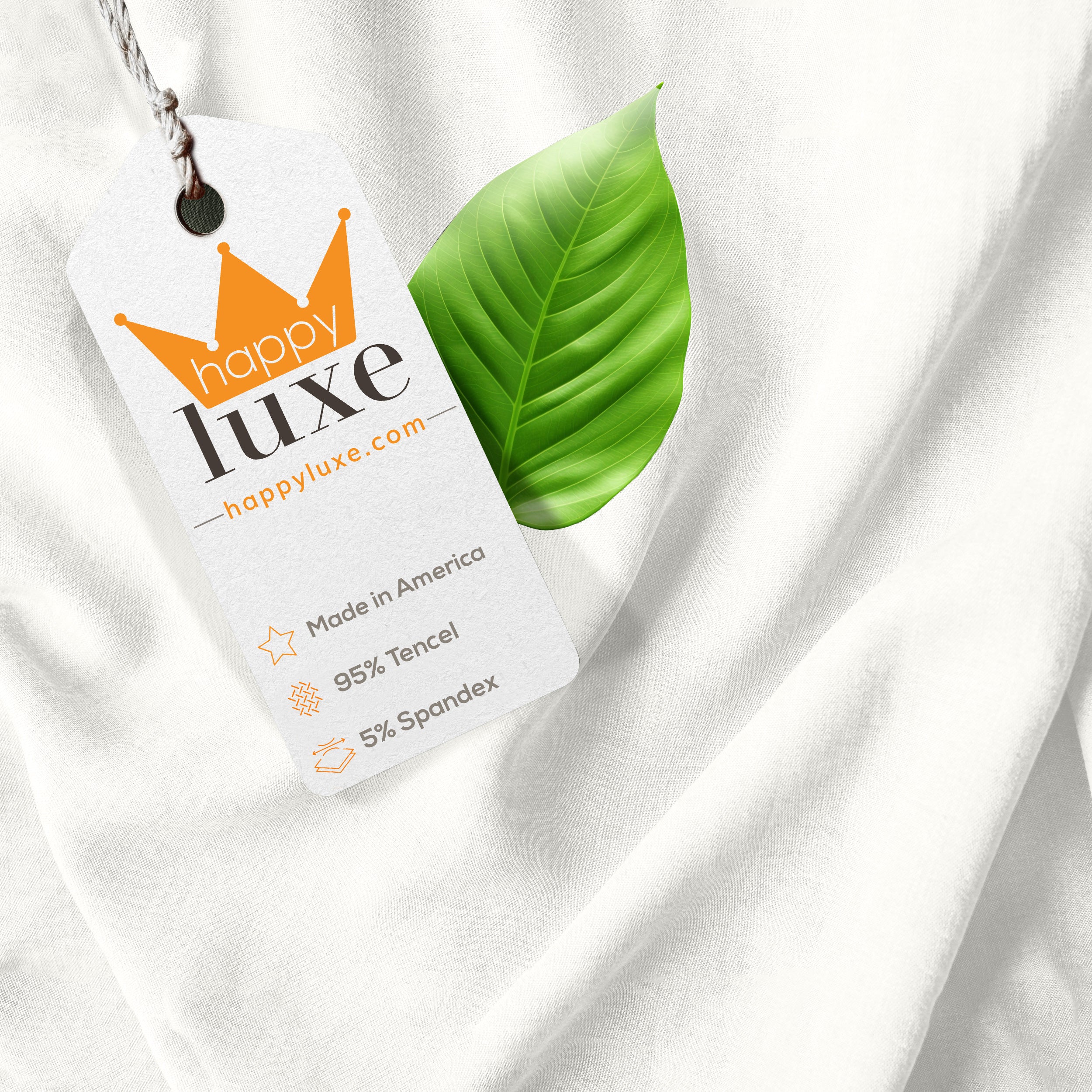 HappyLuxe tag on soft white fabric with green leaf, showcasing 95% Tencel, 5% Spandex, made in America