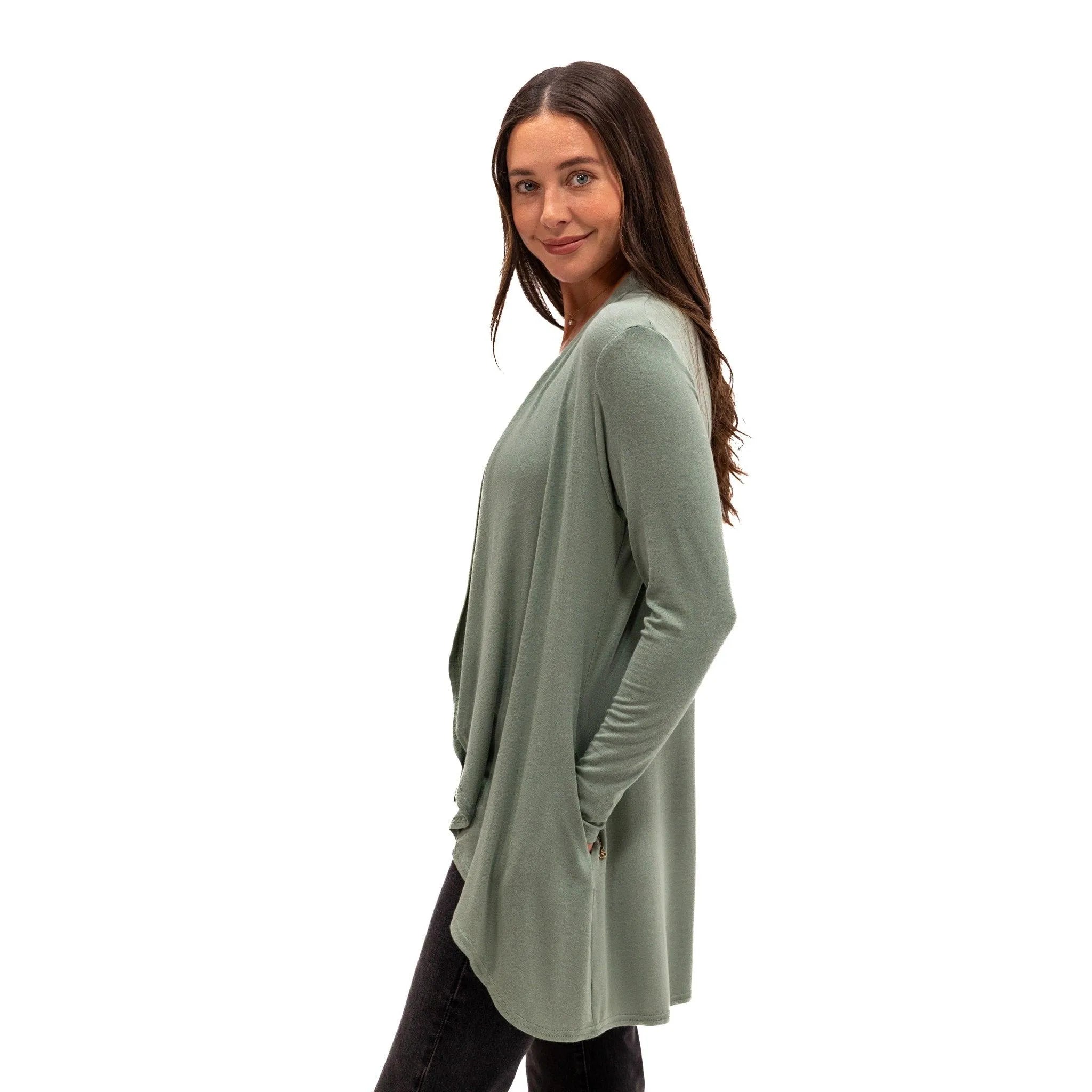 Woman wearing soft sage green long-sleeve travel top with pockets, ideal for comfort on flights or daily wear.