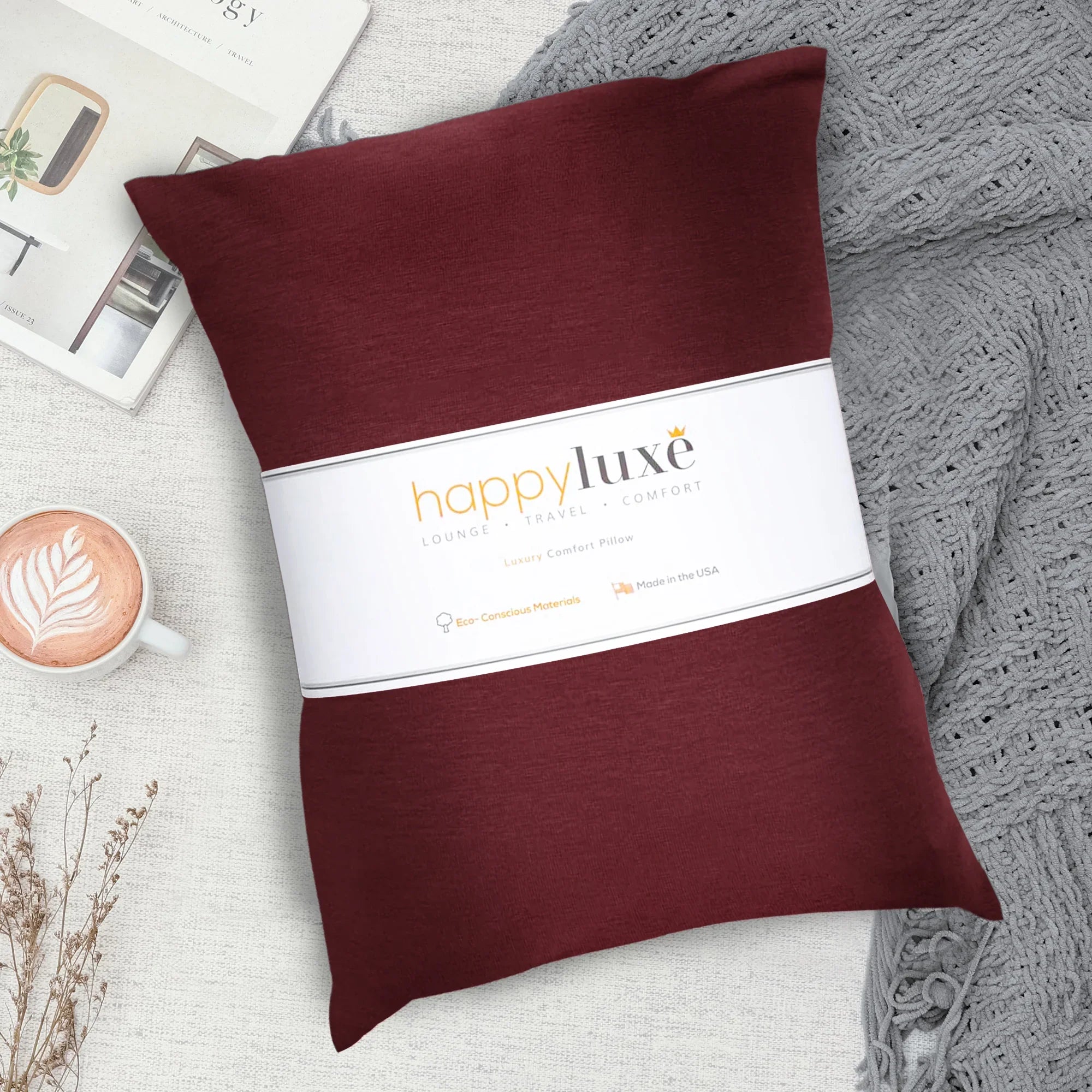 Luxury comfort travel pillow in deep red, eco-conscious materials, styled with latte and cozy knit blanket